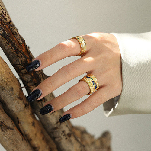 Hand wearing two gold rings with a neutral background