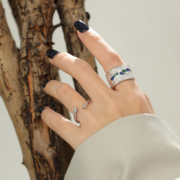 A person's hand displaying a textured S925 sterling silver ring on one finger, with black nail polish and other rings visible in the background.